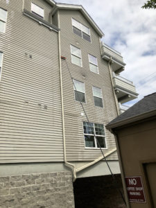 Long water-fed pole cleaning upper windows of a multi-story residential building