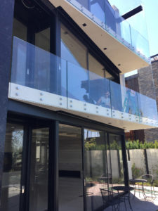 Multi-level home with expansive glass windows, sliding doors, and clear balcony railings